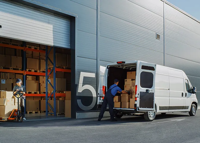 Man loading delivery truck outside of warehouse door.
